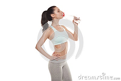 Sporty girl drinking water from a bottle after a workout, fitness training, isolated on white background Stock Photo