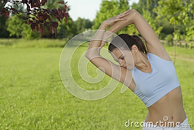 Sporty girl exercising on meadow against the sky Stock Photo