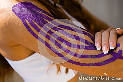 Sporty girl with kinesio tape on her arm. Fixation of the muscles of the biceps with a plaster for kinesitherapy Stock Photo