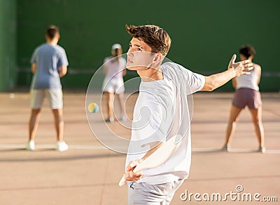 Sporty guy playing pelota with wooden racket on open fronton court Stock Photo