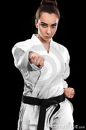 Sporty karate and taekwondo woman in white kimono with black belt on dark background. Sport concept with copy space. Stock Photo