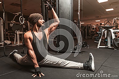 A sporty man in the gym is doing Yoga and Martial Arts exercises. Hanumanasana or Monkey Pose. Stock Photo