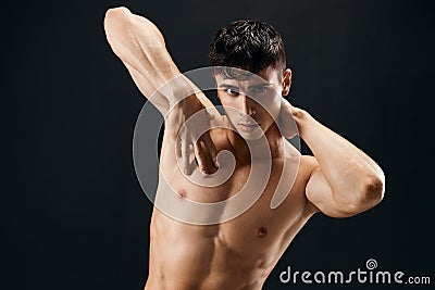 sporty man with muscular muscle body posing against dark background cropped view Stock Photo