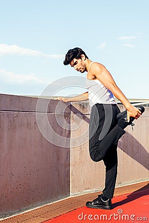 Sporty man stretching leg muscles on concrete wall Stock Photo