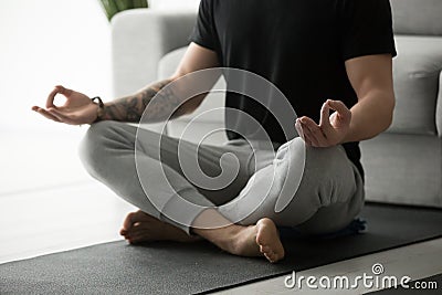 Sporty man with tattoo meditating practicing yoga in lotus pose Stock Photo