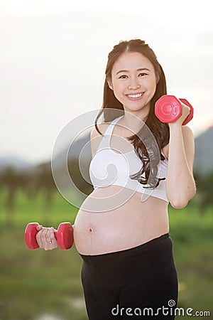 Sporty pregnant asian woman exercising with dumbbells Stock Photo