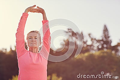Sporty senior woman doing exercise warm-up stretches outdoors Stock Photo