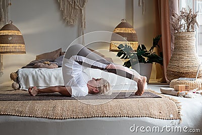 Sporty senior woman doing halasana, plough pose or yin yoga snail posture Stock Photo