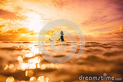 Sporty surf woman in sea at sunset or sunrise. Winter surfing in ocean Stock Photo