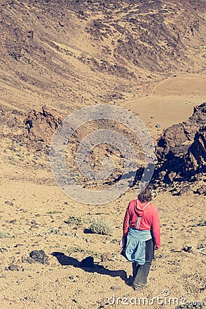 Sporty woman running down volcanic slope lifting dust trail. Stock Photo