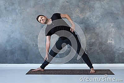 Sporty young man practicing yoga, doing stretching exercise, extended triangle pose Stock Photo