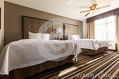 A spotless clean hotel room with two queen size beds covered with clean white bedding Stock Photo