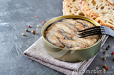 Sprats in an open tin can, stacked in rows, prick on a fork. Stock Photo