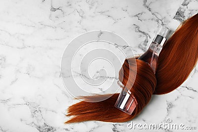 Spray bottle wrapped in lock of hair on white background, flat lay with space for text. Natural cosmetic products Stock Photo