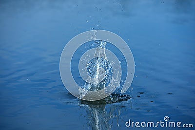 Spray of water from a thrown stone into the water Stock Photo