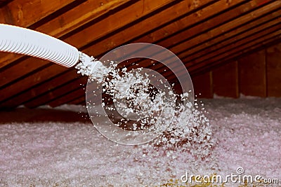 Spraying Blown Fiberglass Insulation for roof - technician spraying foam insulation using plural component gun Stock Photo