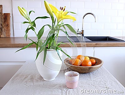 Spring breakfast still life with a cup of coffee and a wooden bowl with oranges. Lily flowers in a vase on a wooden Stock Photo