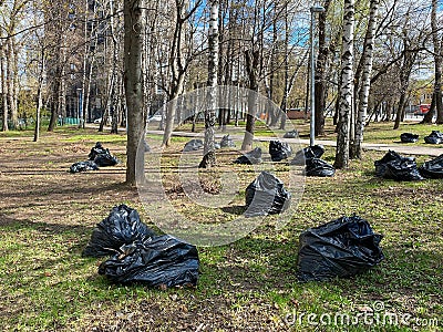 Spring cleaning in public park, black polyethylene trash bags with rubbish Stock Photo