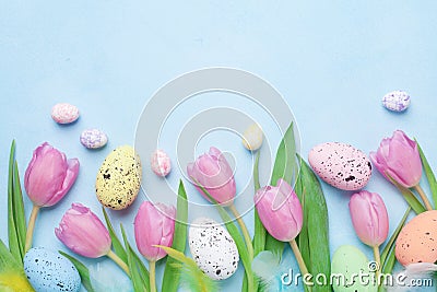 Spring composition with pink tulip, colorful eggs and feathers on blue table top view. Happy Easter card. Stock Photo