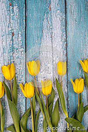 Spring composition of yellow flowers, a tulip, a basket of sweets and eggs on a blue background. Congratulations on Easter. Stock Photo