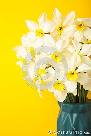 Spring Easter background with daffodils bouquet in vase on yellow background. Vertical photo Stock Photo