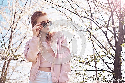 Spring fashion girl outdoors portrait in blooming trees. Beauty Romantic woman in flowers in sunglasses. Sensual Lady. Stock Photo