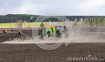 Spring field work, a tractor with a trailed seeder sows seeds in an agricultural field Editorial Stock Photo