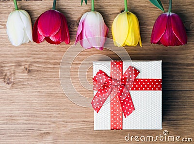 Spring is here. Gift box and tulips on wooden background Stock Photo