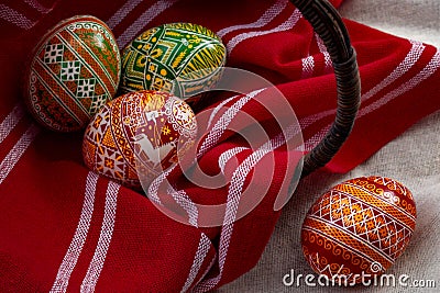 Spring holiday and happy easter concept with three dyed eggs in a rustic vintage wicker basket and red cloth with each egg having Stock Photo