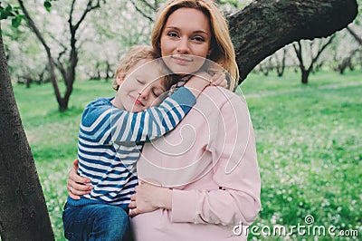 Spring portrait of happy pregnant mother enjoying warm day with child son Stock Photo