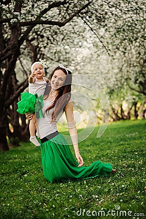 Spring portrait of mother and baby daughter playing outdoor in matching outfit - long skirts and shirts Stock Photo