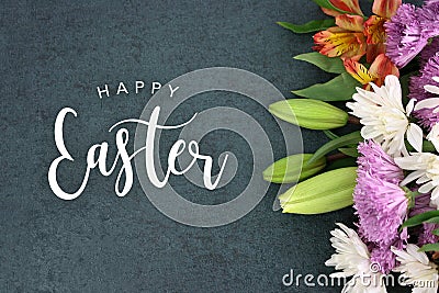 Happy Easter holiday script text over dark background texture and flowers Stock Photo