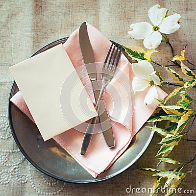 Spring Table Place Setting with dogwood flowers, pink napkin, silverware and a blank card for menu or invitation. Stock Photo