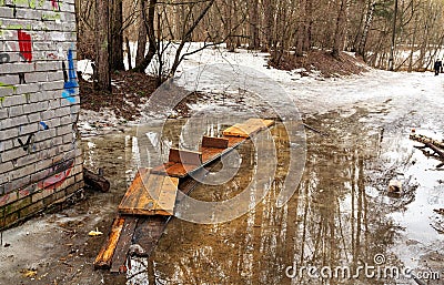 Spring thaw. Wooden bridge over a puddle in the city park. Balashikha, Russia Stock Photo