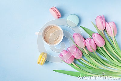 Spring tulip flowers, colorful macaroons and coffee on blue pastel table top view. Beautiful breakfast on Mothers or Womans day. Stock Photo