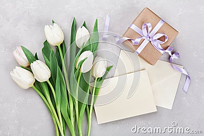 Spring tulip flowers, gift box and paper card on gray stone table from above in flat lay style. Greeting for Womens or Mothers Day Stock Photo