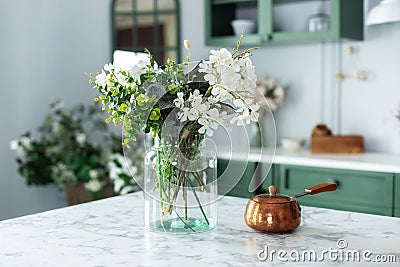 Spring wild flowers in vase and turk with coffee in kitchen table. Bouquet of flowers and plants in glass vase at home. Stock Photo