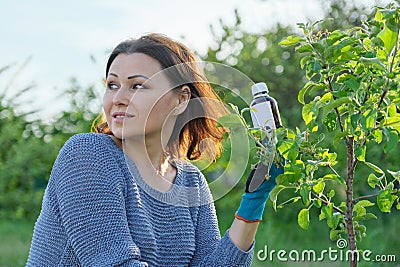 Spring work in the garden, bottle of chemical fertilizer, fungicide in hand Stock Photo