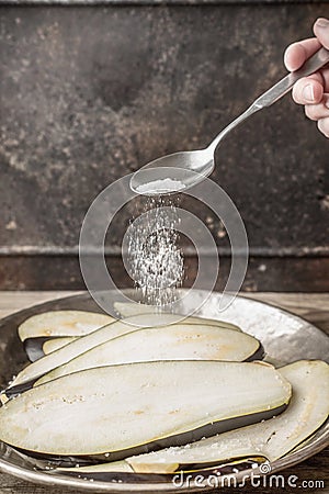 Sprinkling salt on the sliced eggplants vertical Stock Photo