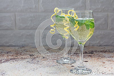 Spritzer cocktail with white wine, mint and ice, decorated with spiral lemon zest, copy space Stock Photo