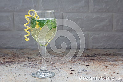 Spritzer cocktail with white wine, mint and ice, decorated with spiral lemon zest, copy space Stock Photo