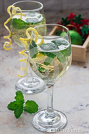 Spritzer cocktail with white wine, mint and ice, decorated with spiral lemon zest Stock Photo