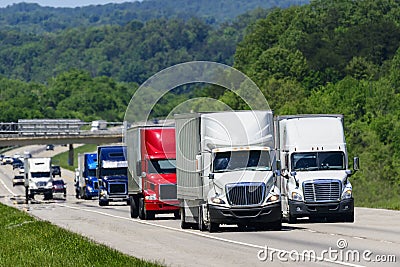 A squadron of eighteen-wheelers lead the way down an interstate highway in eastern Tennessee Stock Photo