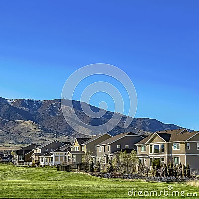 Square Charming homes and towering mountain under clear blue on a sunny day Stock Photo