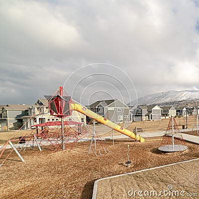 Square Childrens playground against snow capped mountain and cloudy sky in winter Stock Photo