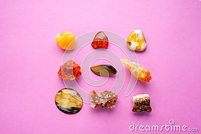 A square of different minerals on pink background. Spiritual amber, calcite, Aragonite, Simbercite, Jasper, Tiger`s eye Stock Photo