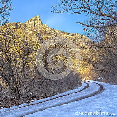 Square Dirt road in snowy Provo Canyon against mountain and blue sky in winter Stock Photo