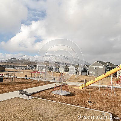 Square frame Childrens playground against snow capped mountain and cloudy sky in winter Stock Photo