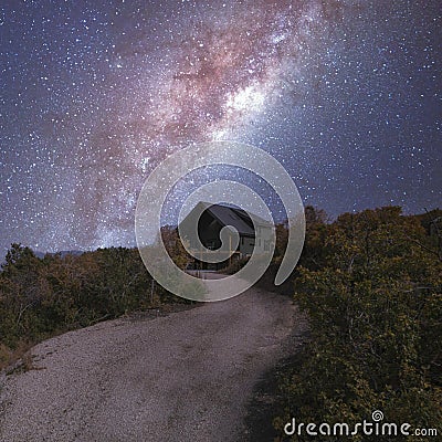 Square frame Path in the middle of a shrubland leading to a house under an aesthetic composite milky way Stock Photo
