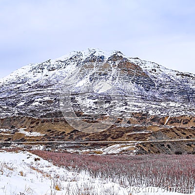 Square Panoramic view of an immense mountain dusted with snow against a cloudy sky Stock Photo